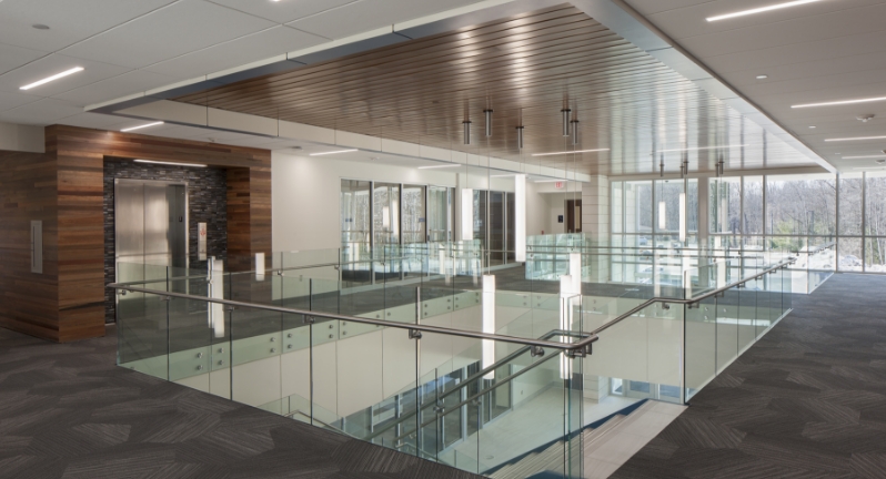 An image of the second floor of a building with a glass railing and staircase