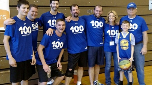 A group in a gym blue shirts a child in the front is holding a basketball